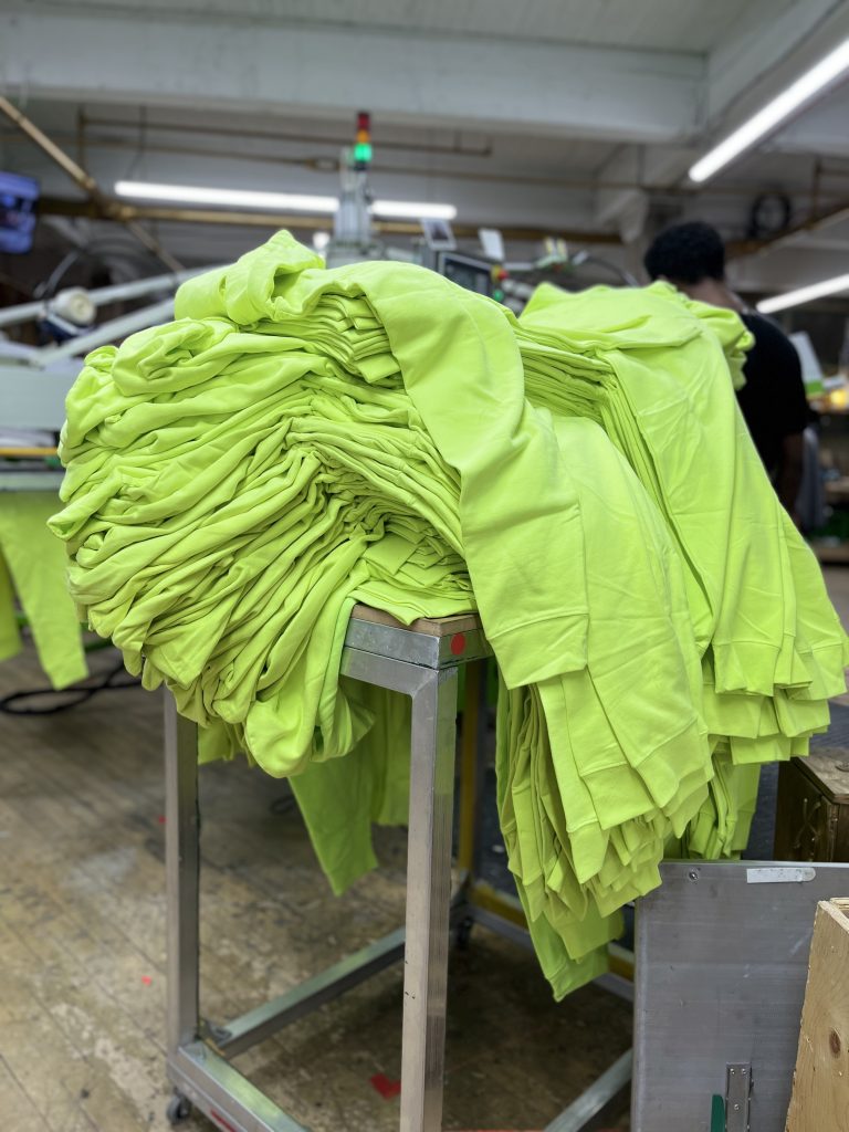 Cart stacked with freshly printed lime green tees on the shop floor