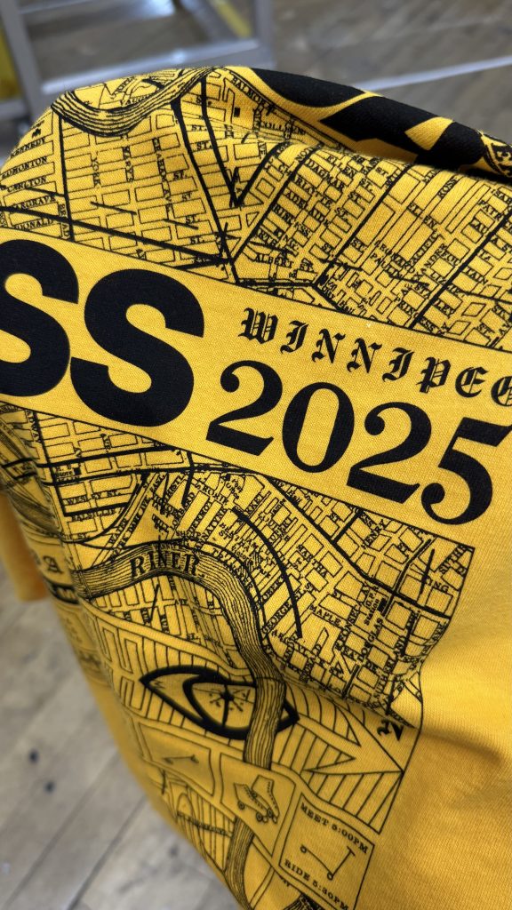 Yellow tee printed with a black Winnipeg street map and WINNIPEG 2025 lettering across it
